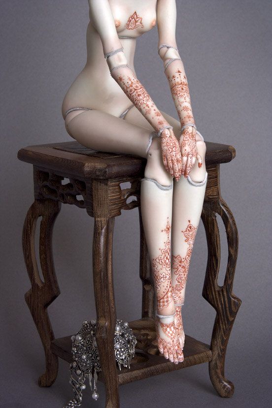 a naked woman sitting on top of a wooden chair