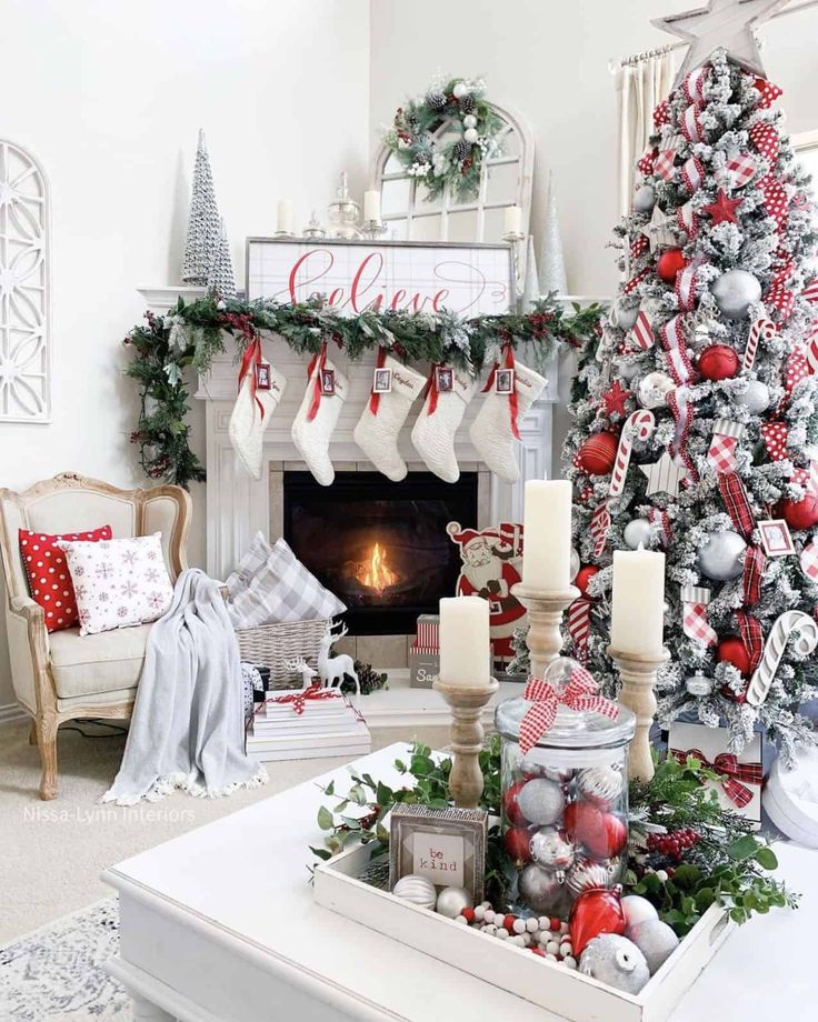 a living room decorated for christmas with red and silver decorations on the fireplace mantel