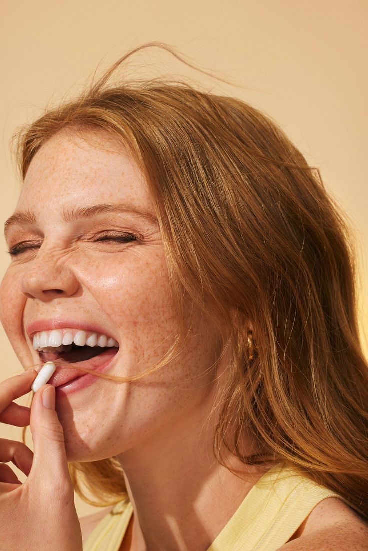 a woman brushing her teeth with an electric toothbrush