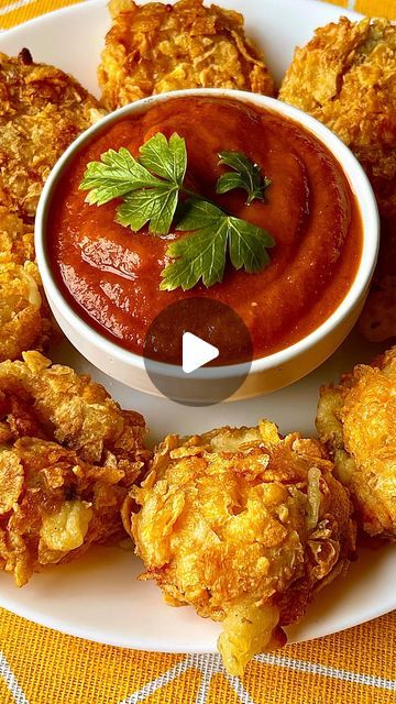 a white plate topped with fried food next to a bowl of sauce