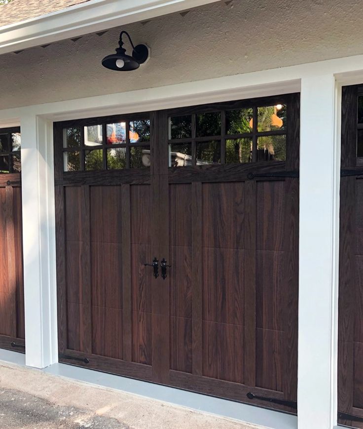 two brown garage doors on the side of a house