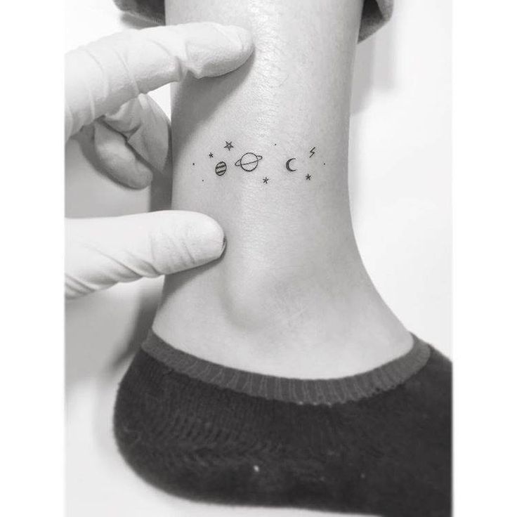 a person with a small tattoo on their ankle that has the moon and stars above them