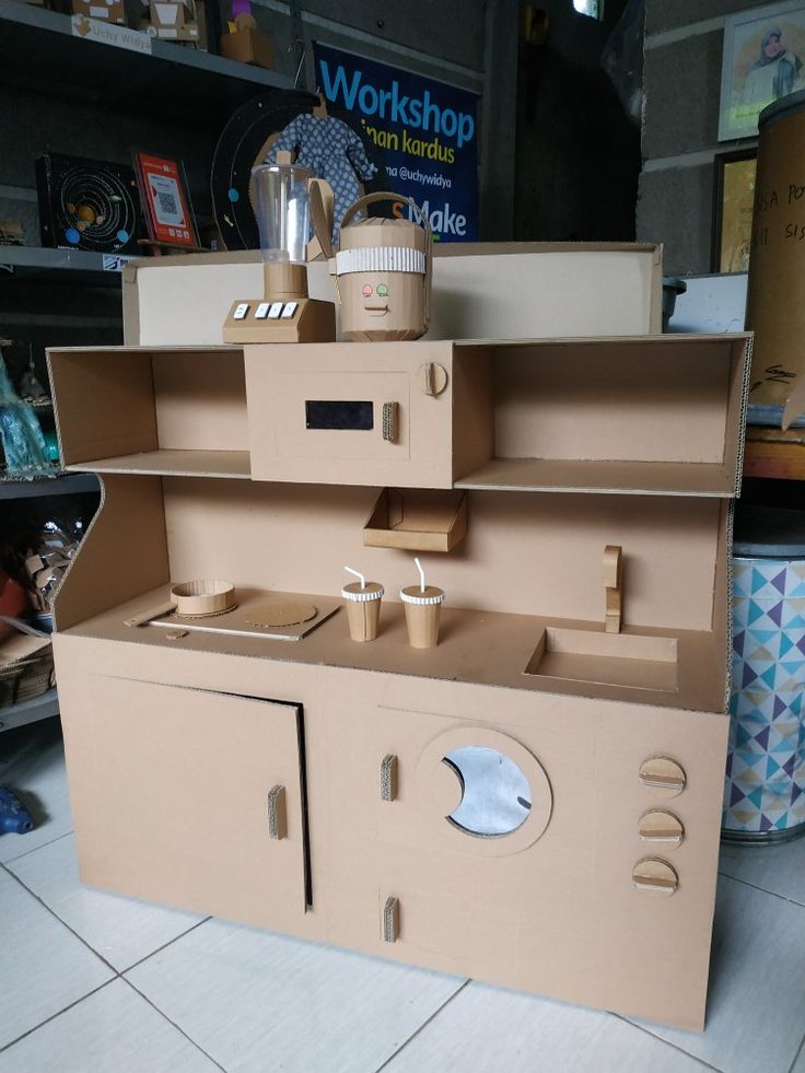 an oven made out of cardboard sitting on top of a floor next to a shelf