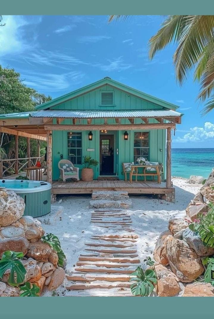 a house on the beach with stairs leading up to it and a hot tub in front