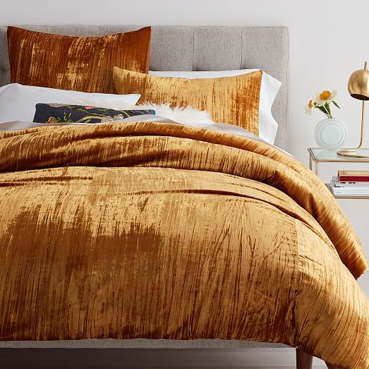 a bed with gold comforter and pillows on it