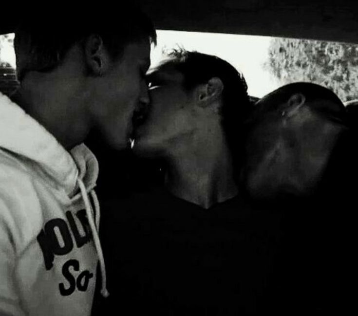 three people kissing in the back seat of a car