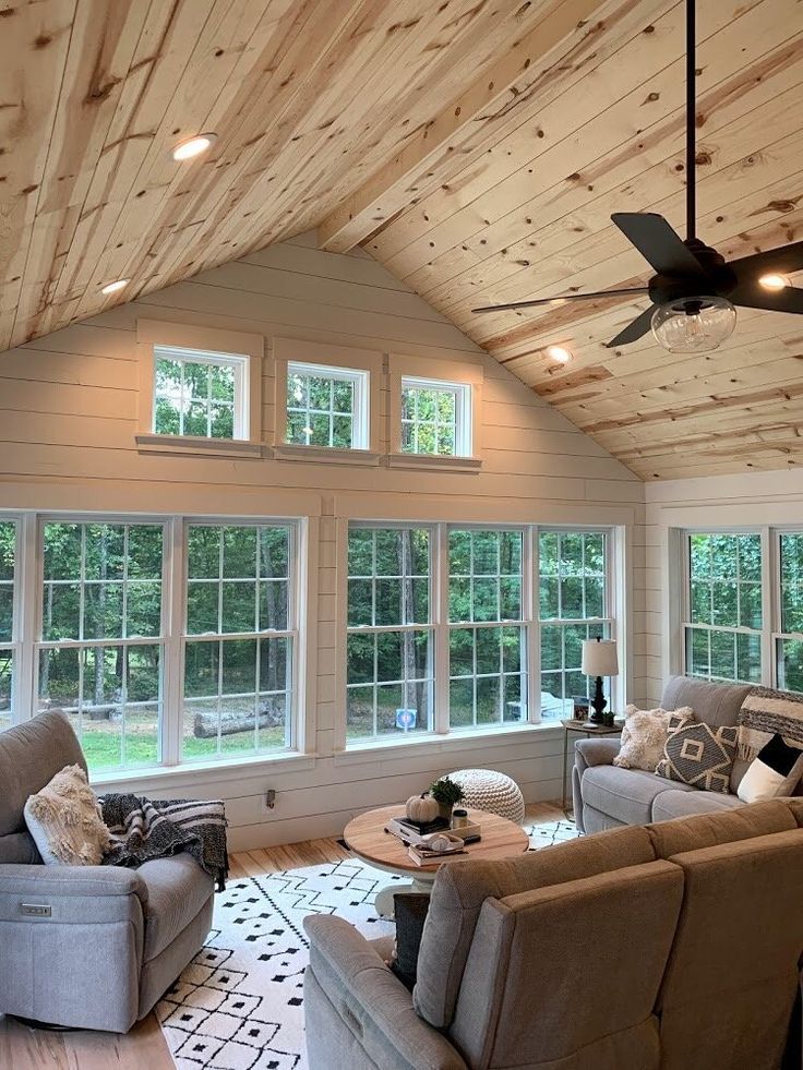 a living room filled with furniture and windows covered in wood planks on the ceiling