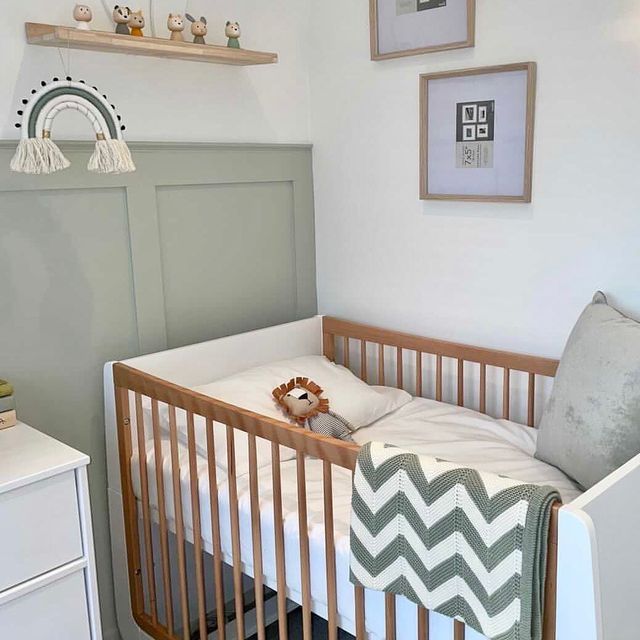 a baby's crib in the corner of a room with pictures on the wall