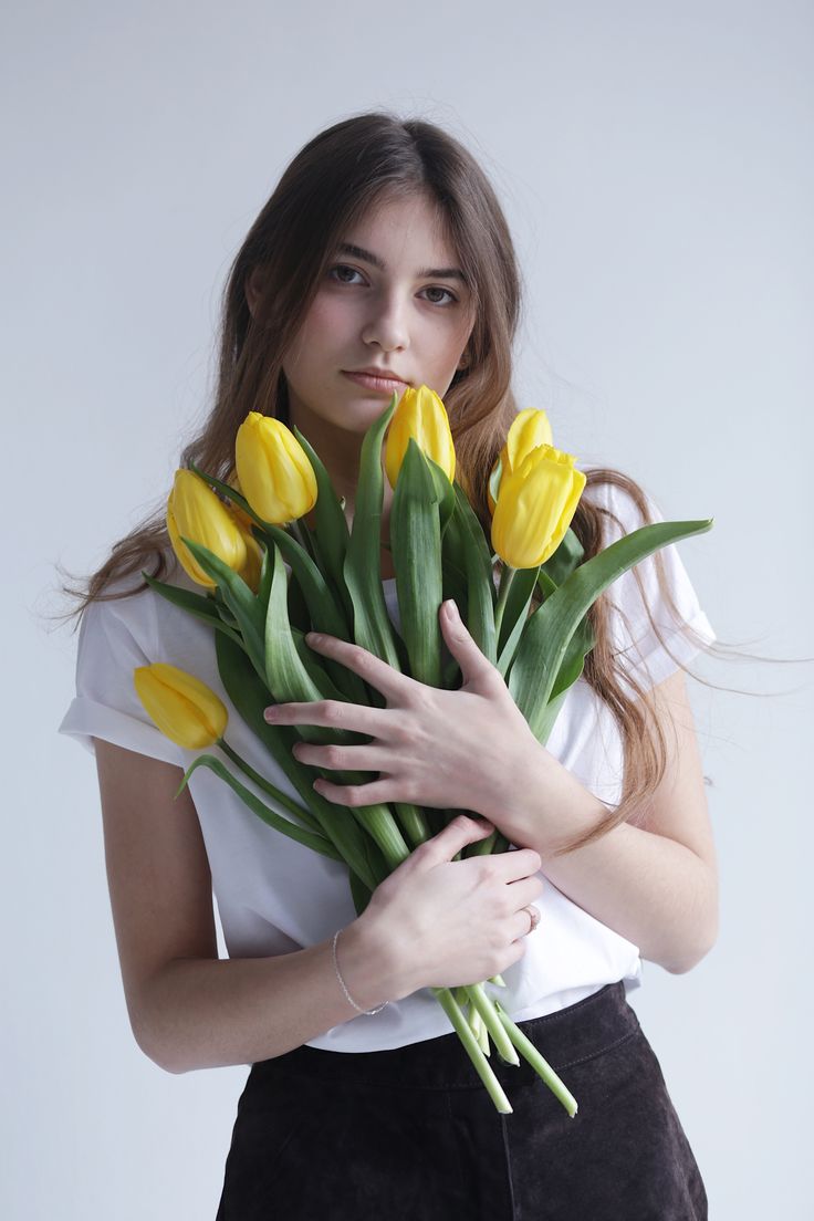 a woman holding yellow tulips in her hands