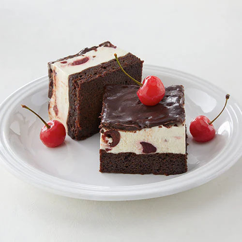 two pieces of cake on a plate with cherries