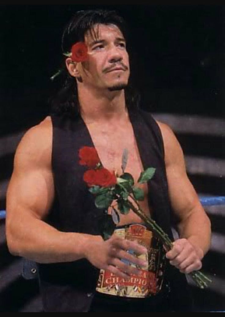 a man with long hair and no shirt holding flowers