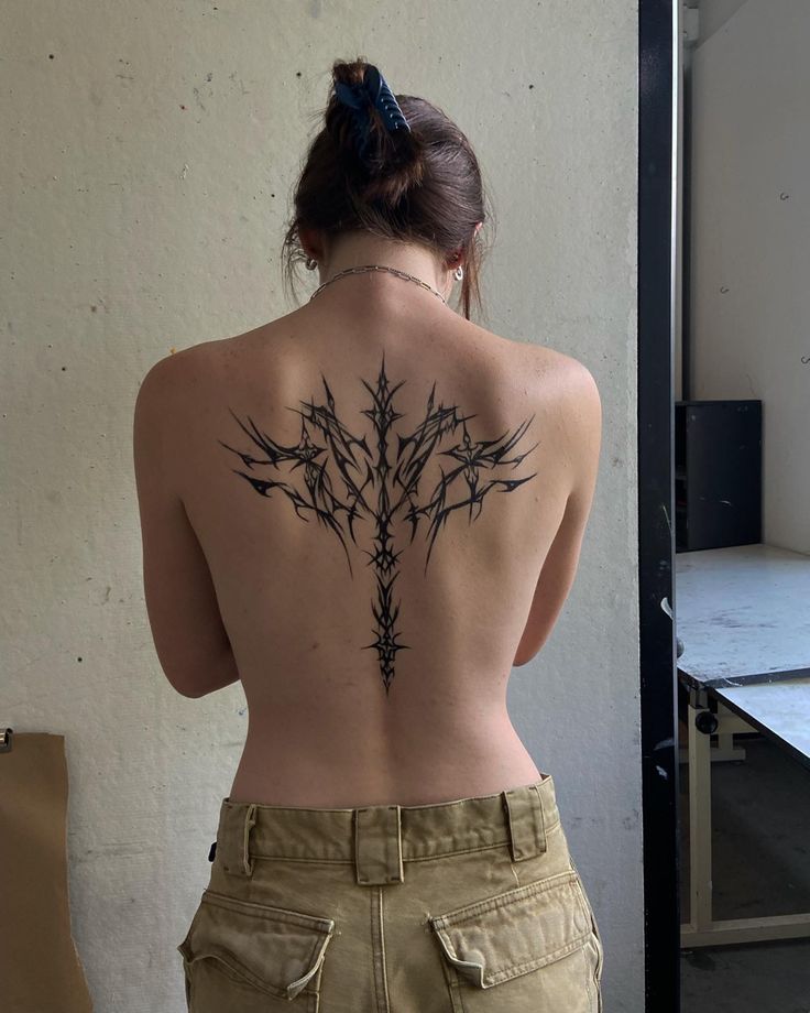 a woman with a tattoo on her back is standing in front of a table and chair