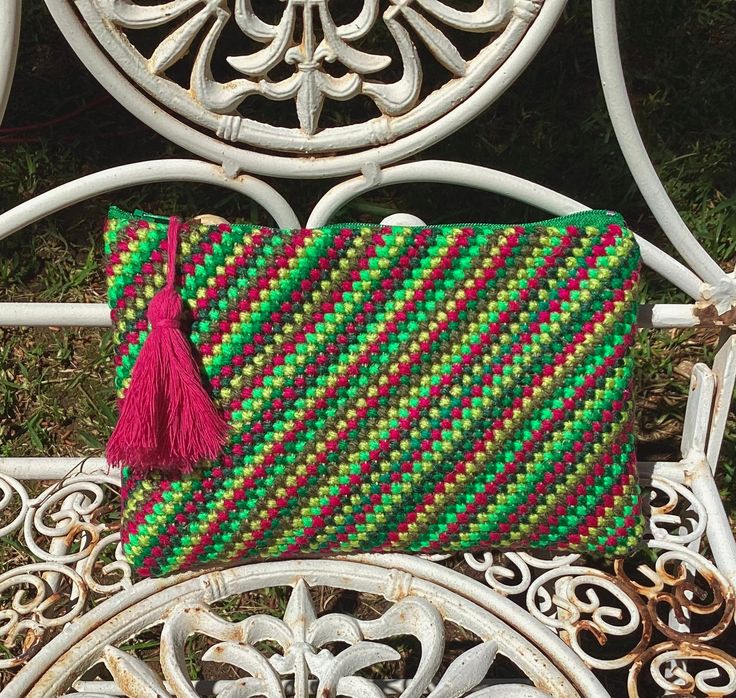 a green and red bag sitting on top of a white chair next to another purse