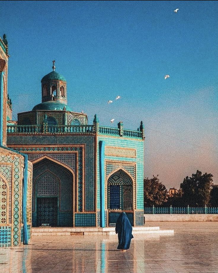 a person standing in front of a building with blue and green tiles on the walls