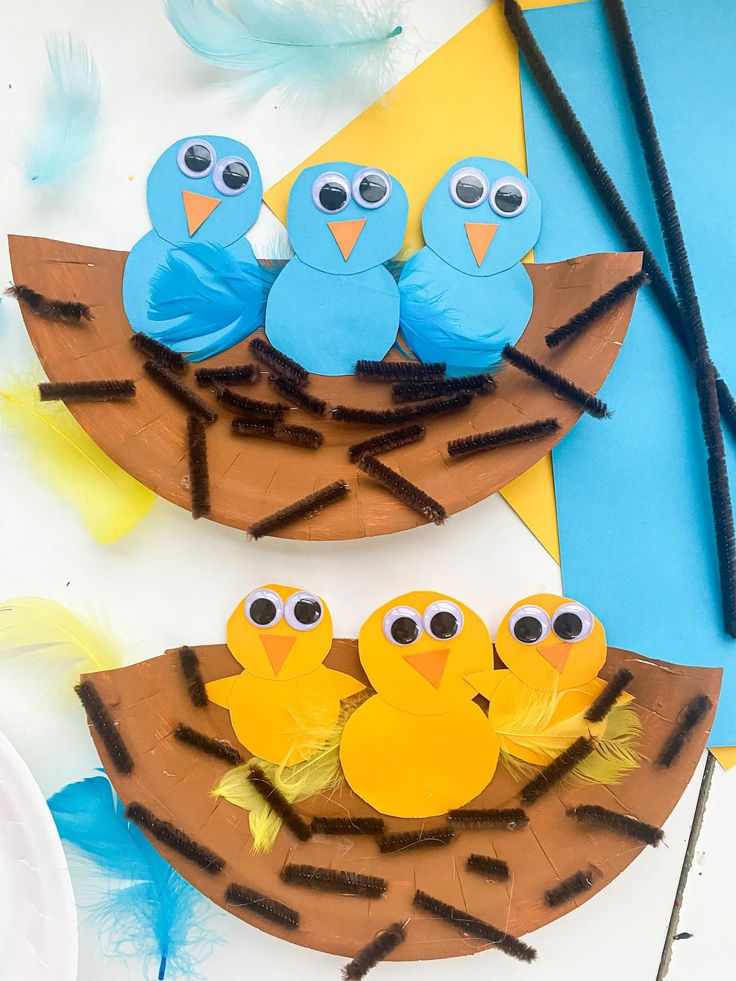 paper plate birds sitting on top of a bird nest made out of cardboard and string