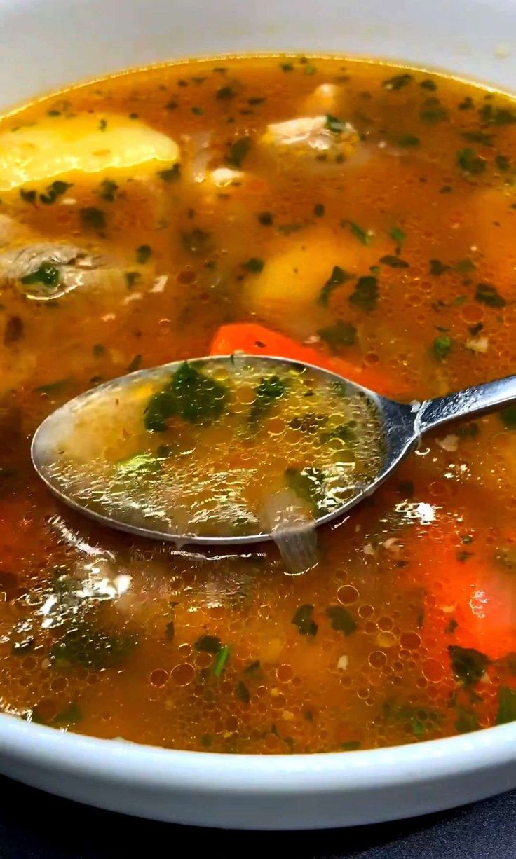 a spoon full of soup with broth and carrots