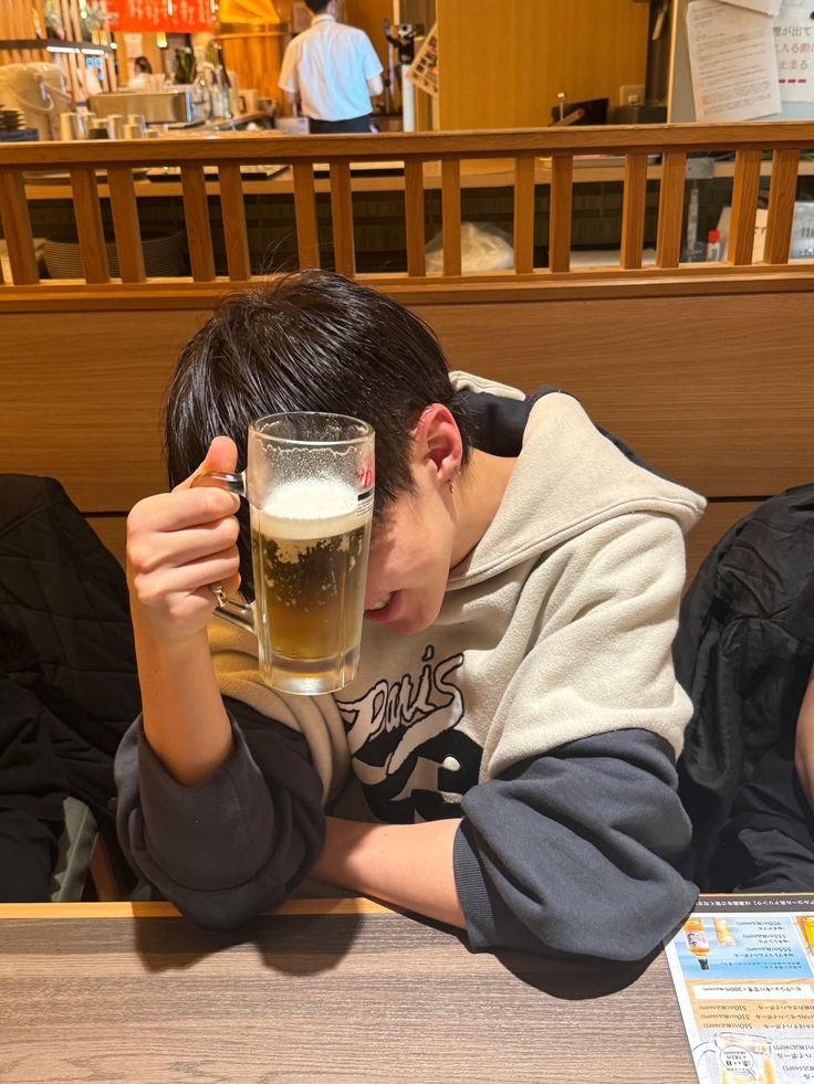 a man sitting at a table with a glass of beer in front of his face