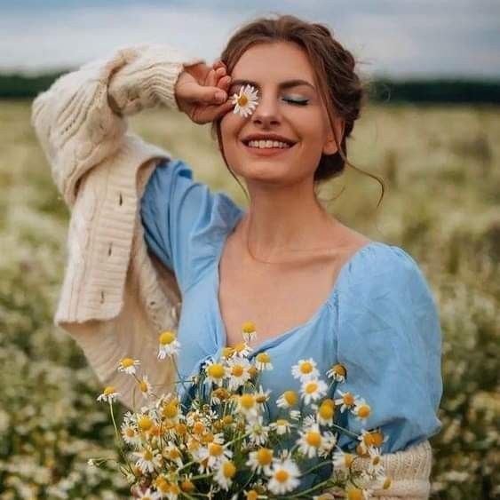 a woman holding a bouquet of daisies in a field