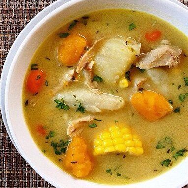 a white bowl filled with chicken and corn soup on top of a cloth covered table