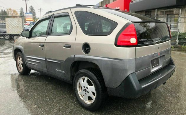 the back end of a silver car parked in a parking lot