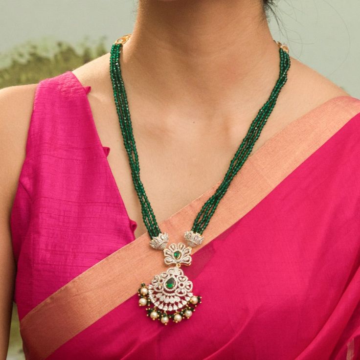 Description : Discover regal opulence with the Amira CZ necklace from Tarinika's festive collection. Inspired by classic Indian designs, this necklace is handcrafted with CZ stones & three-layer emerald beads tassel on gold polish to highlight your festive outfit. Details & Specifications: Materials used: CZ Stone with White Gold Plating Weight - Necklace 42.93 gms Length - Necklace 29 cms Make it custom Want to make it a custom necklace? Sure! Reach out to us at support@tarinika.com and we’ll b Festive Kundan Emerald Necklace For Receptions, Elegant Long Kundan Necklace With Latkans, Temple Jewelry Necklace With Latkans For Reception, Traditional Kundan Emerald Necklace For Reception, Festive Bollywood Chandbali Emerald Necklace, Traditional Gold Emerald Necklace For Reception, Festive Emerald Kundan Chandbali Necklace, Kundan Emerald Necklace For Celebration Festivals, Elegant Kundan Temple Necklace With Gold Beads