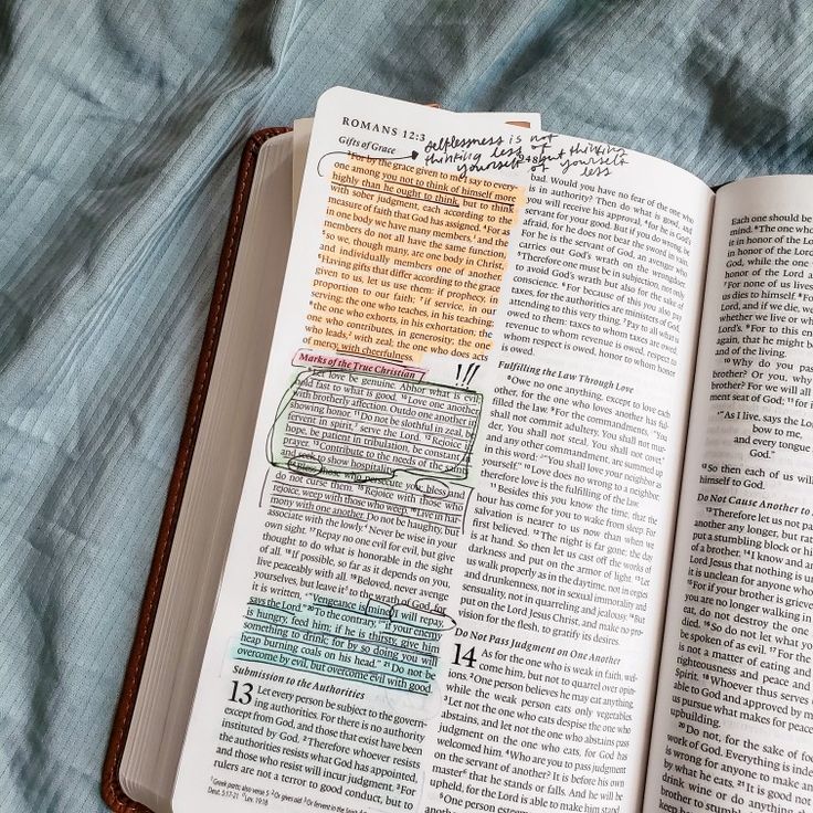 an open book with writing on it laying on top of a blue bed spreaded sheet