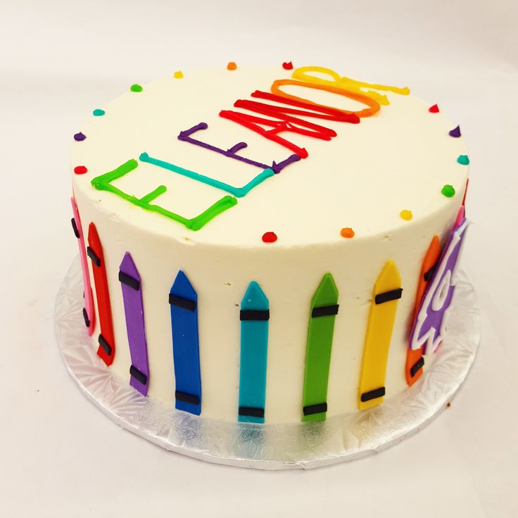 a birthday cake decorated with colorful crayons and the words happy on it's frosting