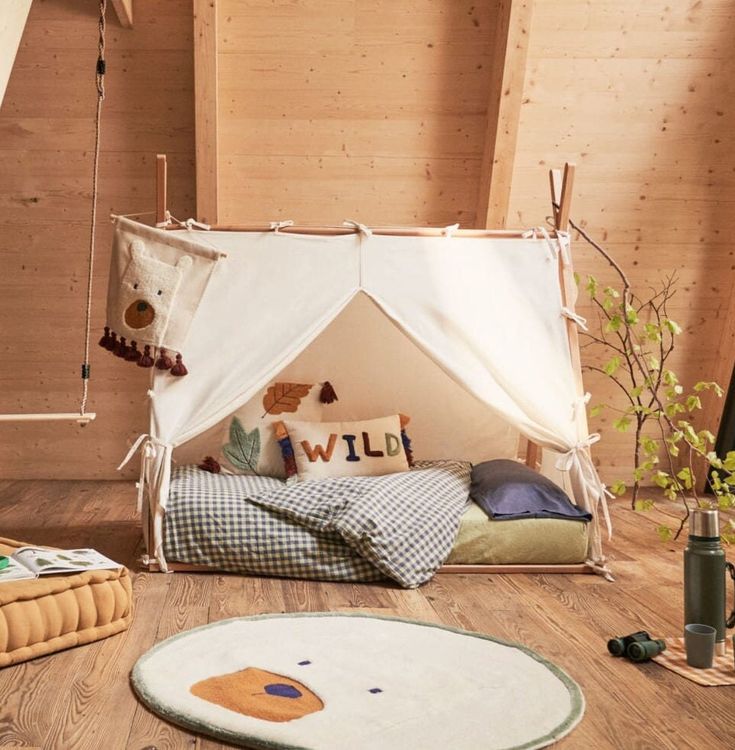 a bed with a canopy and pillows on the floor in a room that has wooden walls