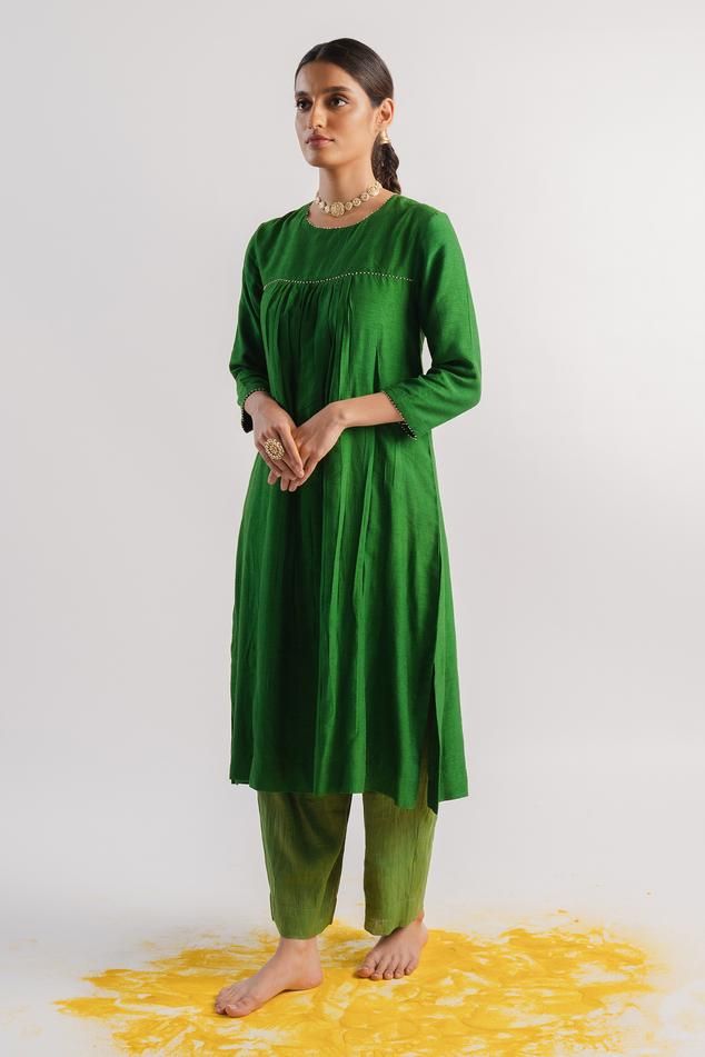 Green slub silk A-line kurta with beaded hand embroidered neckline, yoke and sleeve hems. Comes with tissue pant.
Components: 2
Pattern: Hand embroidered
Type Of Work: Beads
Neckline: Round
Sleeve Type: Three quarter
Fabric: Kurta : Slub silk, Pant : Tissue
Color: Green
Other Details: 
Closure : Kurta - Back potli buttons
Occasion: Puja - Aza Fashions Silk Pant, A Line Kurta, Beaded Neckline, Embroidered Neckline, Fashion App, Pant Set, Set For Women, Aza Fashion, Sleeve Type