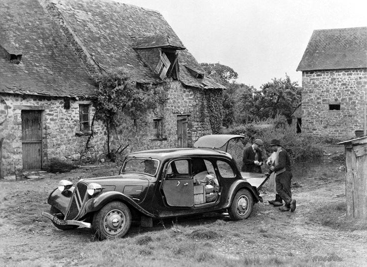 an old black and white photo of two men standing next to a car