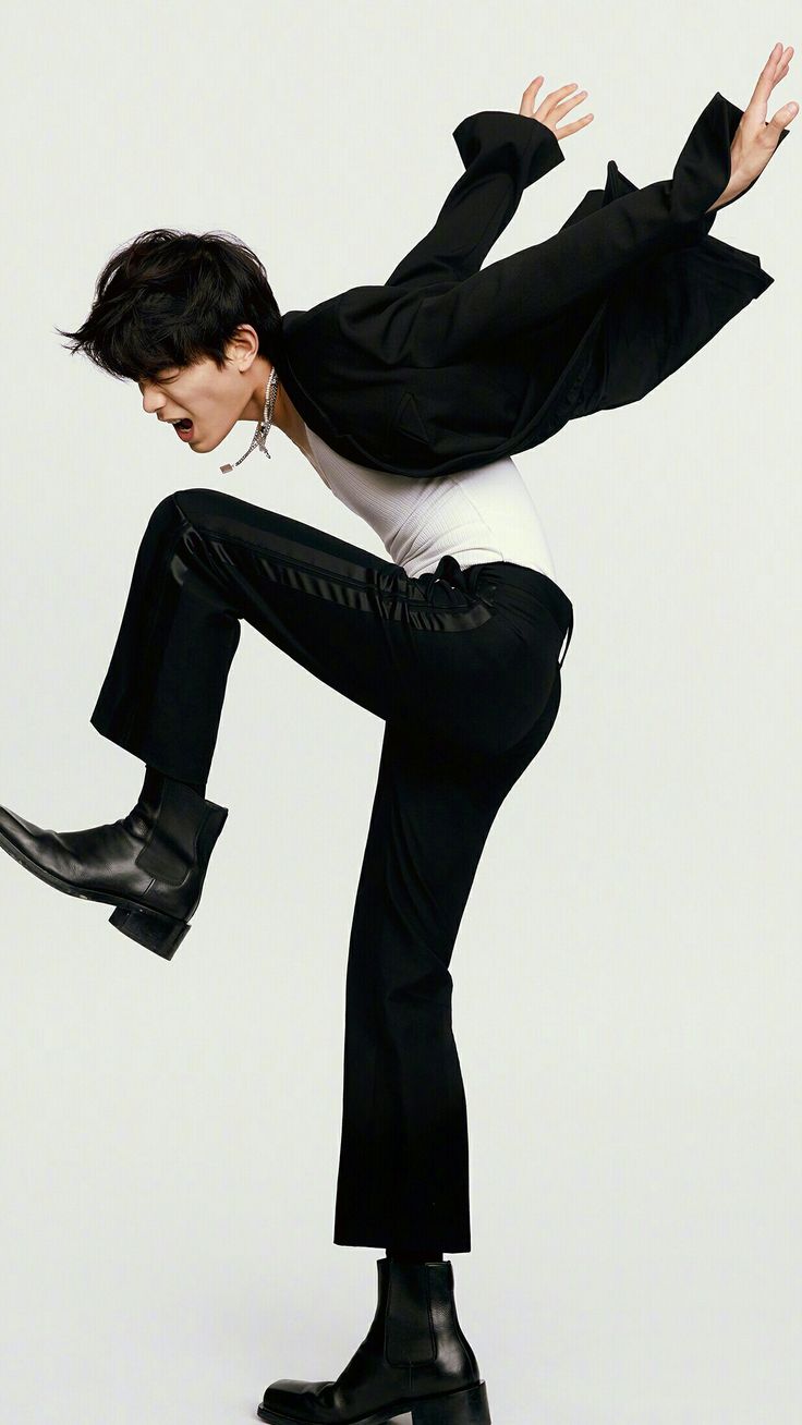 a man in black jacket and white shirt doing a trick on a skateboard with his legs