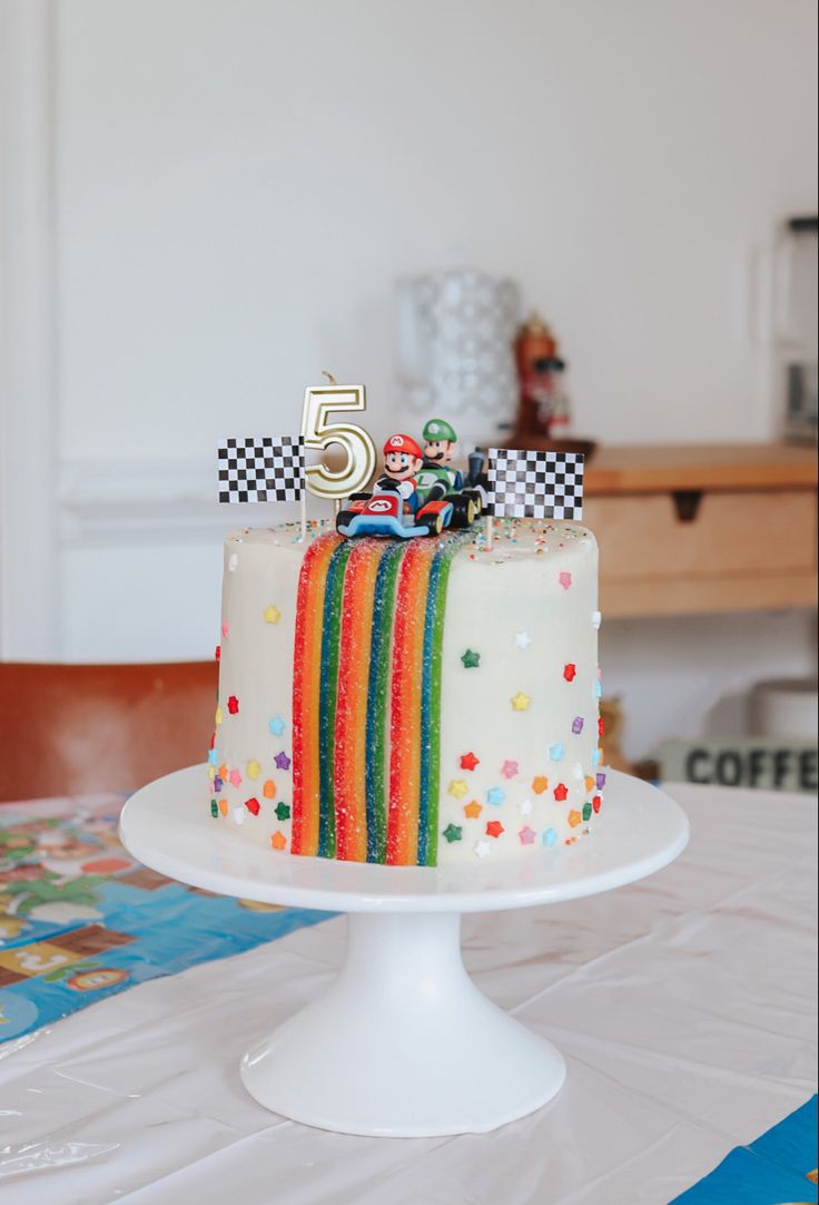 a birthday cake decorated with rainbows and cars