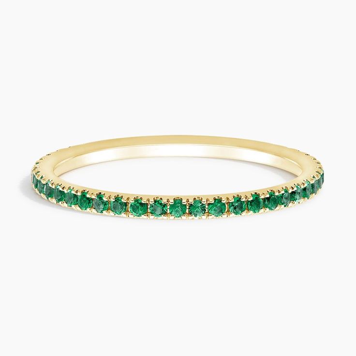 a yellow gold band with green stones