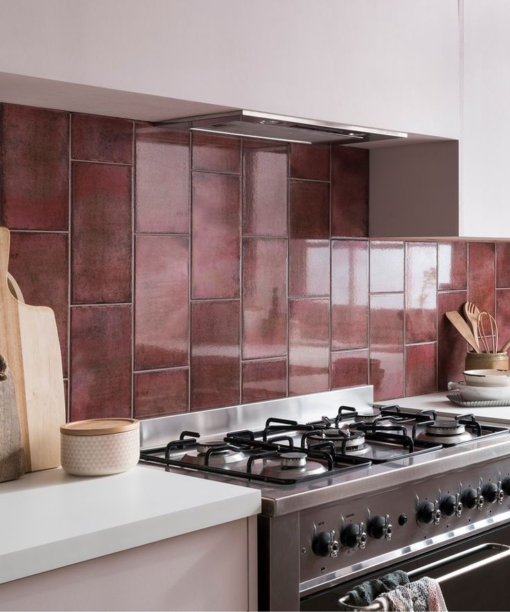 a stove top oven sitting inside of a kitchen next to a wooden cutting board and utensils