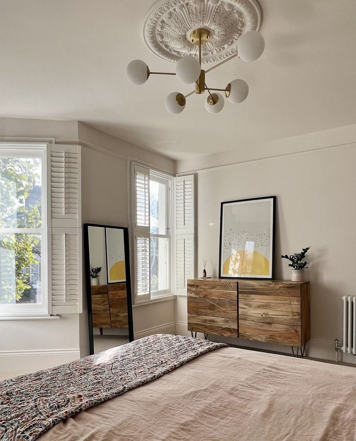 a bedroom with a bed, dresser and mirror on the wall in front of it