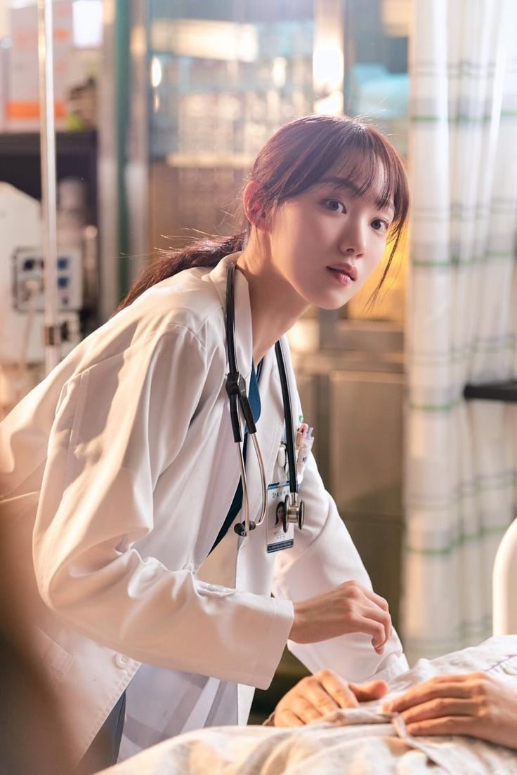 a woman in a hospital bed with a stethoscope around her neck and wearing a white lab coat