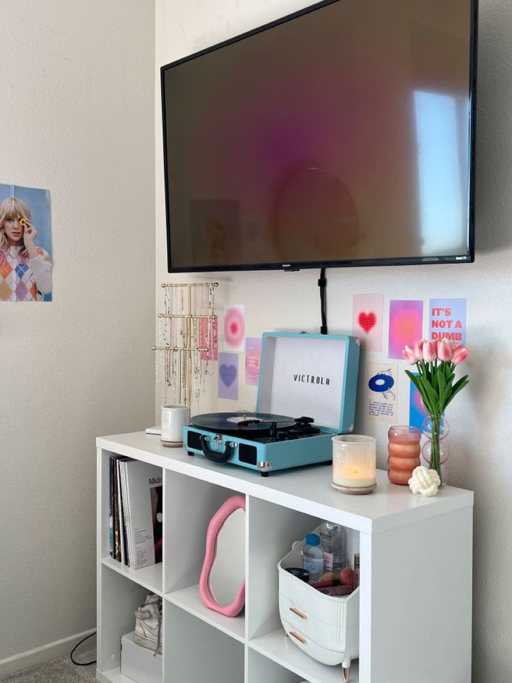 a flat screen tv mounted to the side of a wall next to a book shelf