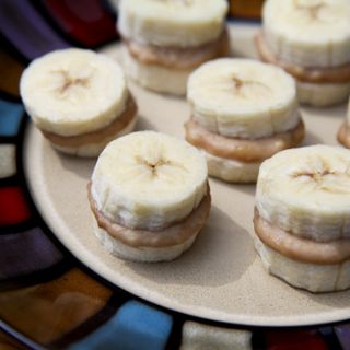 a white plate topped with mini sandwiches covered in banana slices