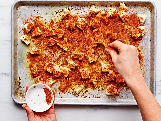 a person is spreading sauce on top of some food in a baking pan with one hand