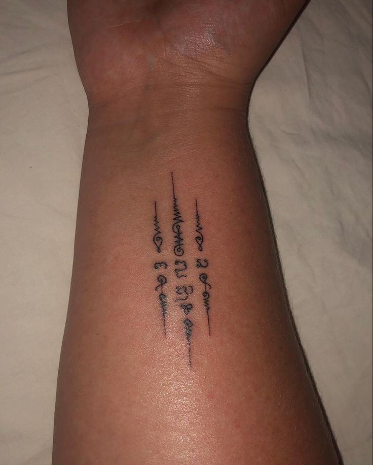 a person with a tattoo on their arm that has numbers and letters written in cursive writing