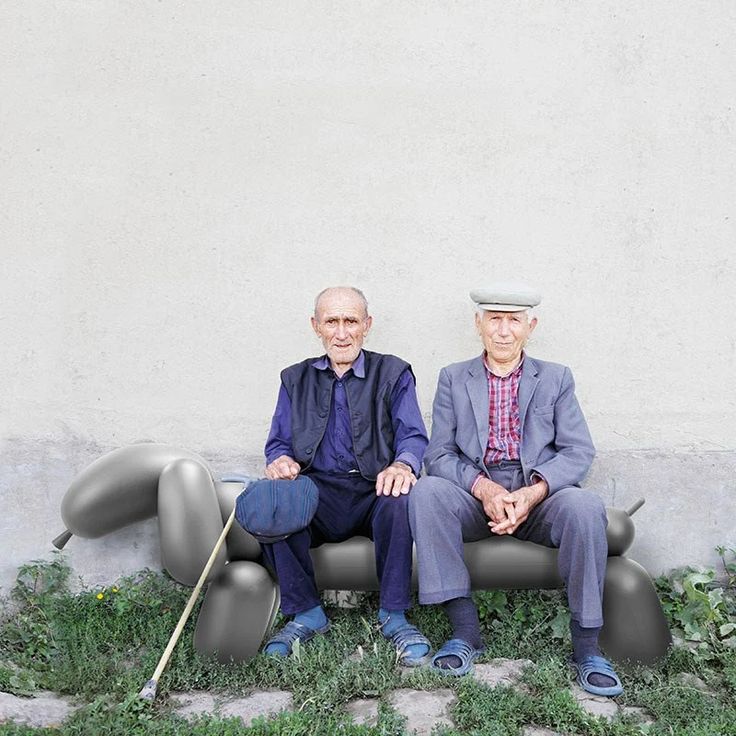 two older men sitting next to each other in front of a wall with grass growing on it