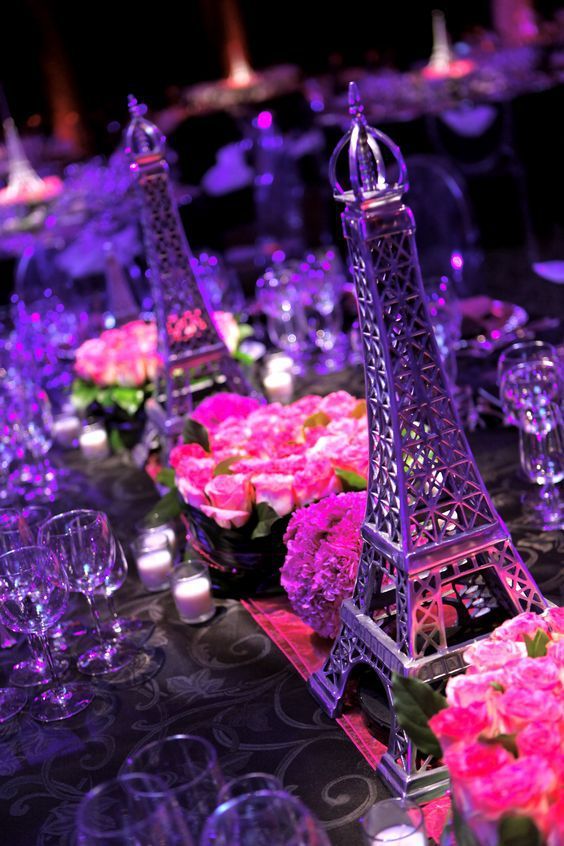 the table is set with pink flowers and candles for an elegant dinner in front of the eiffel tower