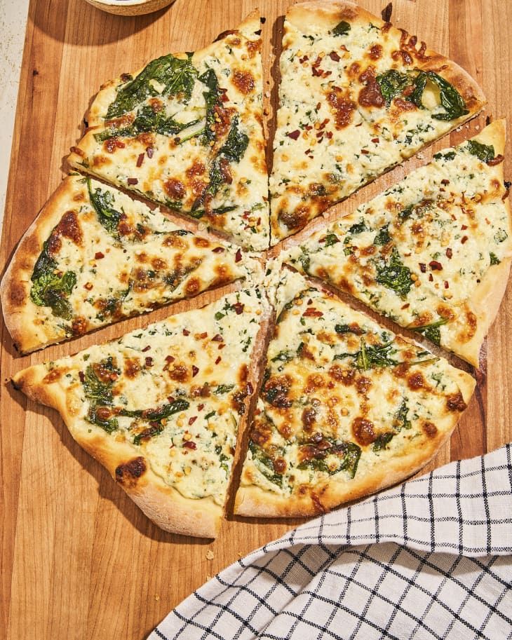 a sliced pizza sitting on top of a wooden cutting board