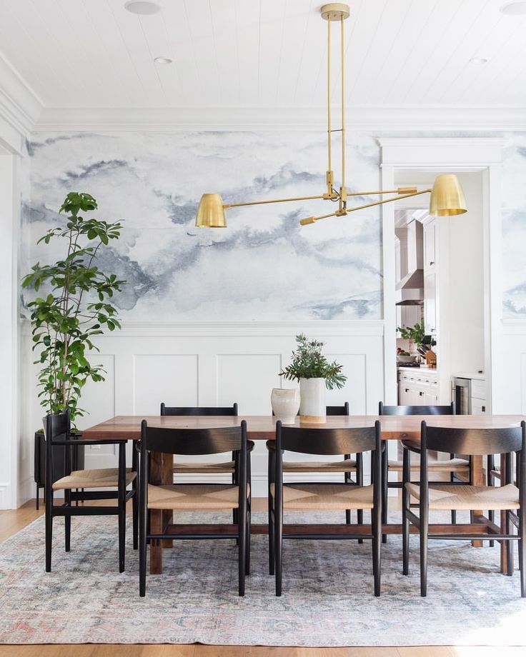 the dining room table and chairs are in front of a wall with clouds painted on it