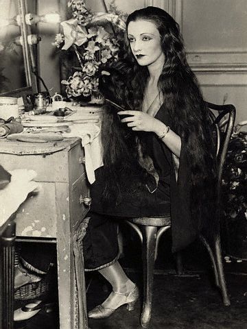 a woman sitting at a table with flowers in the background