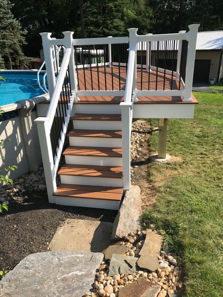 a wooden deck next to a swimming pool with steps leading up to the upper level