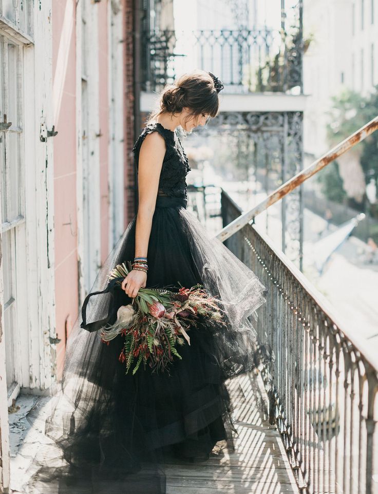 a woman in a black dress is walking down the stairs