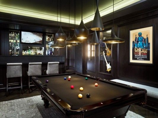 a pool table in the middle of a room with bar lights and chairs around it