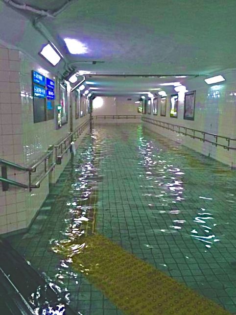 an empty swimming pool with green tiles and yellow caution tape on the floor next to it