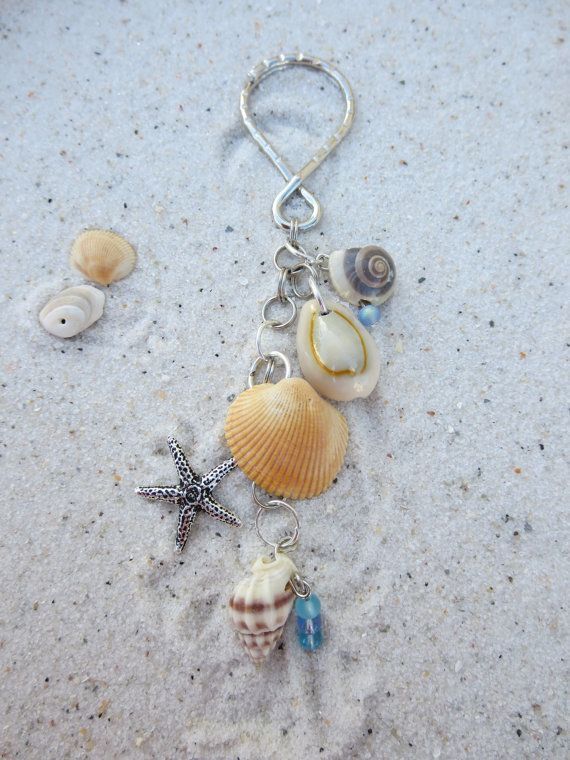 a keychain with shells and starfishs on it sitting in the sand